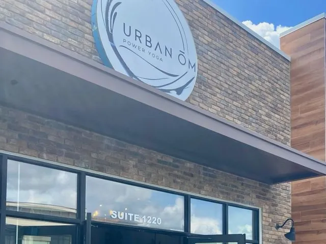 Urban Ōm Power Yoga round sign above the brick storefront entrance at Suite 1220 in Heathrow